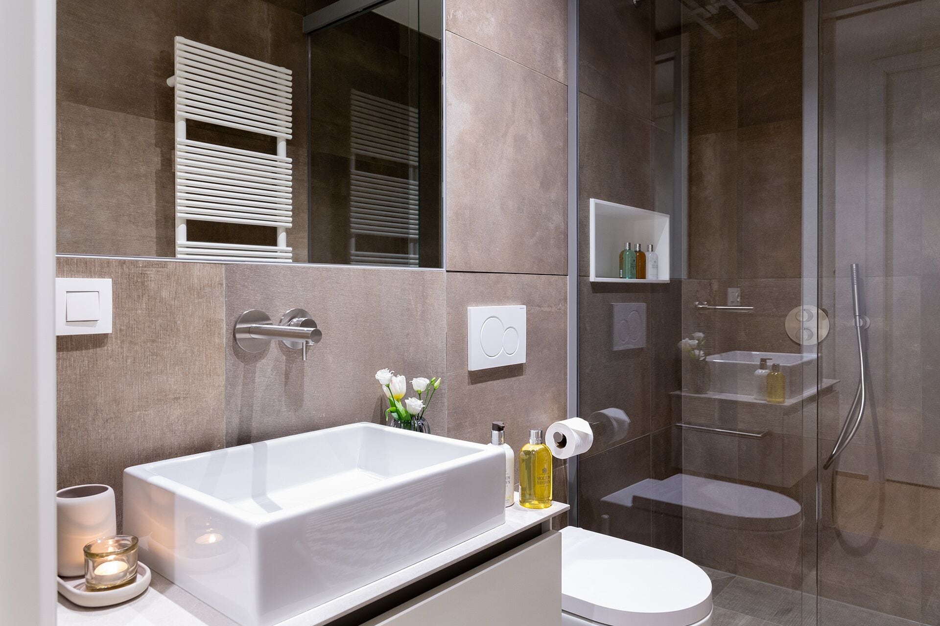 A modern bathroom with a large bathtub, a toilet, and a glass-enclosed shower area.