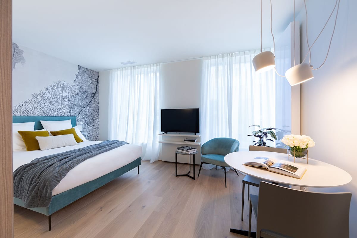 Une chambre d’hôtel moderne équipée d’un lit, d’un bureau, d’une chaise et d’un téléviseur.