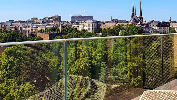 A cityscape with a prominent church spire, a modern building, and a green park area. - The Central City - Luxury ApartHotel (Luxembourg City)