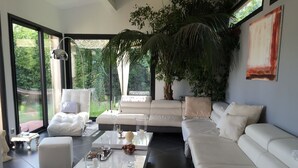 A modern living room with a white sofa, a coffee table, and a large window overlooking a garden. - Villa with swimming pool, 10 mn from Montpellier, 20 mn from the beaches (Pignan)
