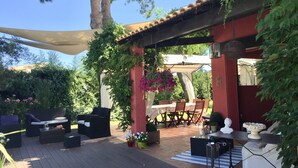 A covered outdoor patio with a wooden deck, outdoor furniture, and a pergola with climbing plants. - Villa with swimming pool, 10 mn from Montpellier, 20 mn from the beaches (Pignan)