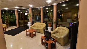 A lobby with leather chairs, a wooden table, and a computer. - Hotel Forum (Ploiesti)