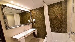Un baño moderno con un espejo grande, un lavabo blanco, una bañera y una cortina de ducha.