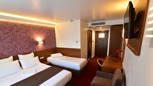 Habitación de hotel con dos camas, un sofá, un televisor y un escritorio.