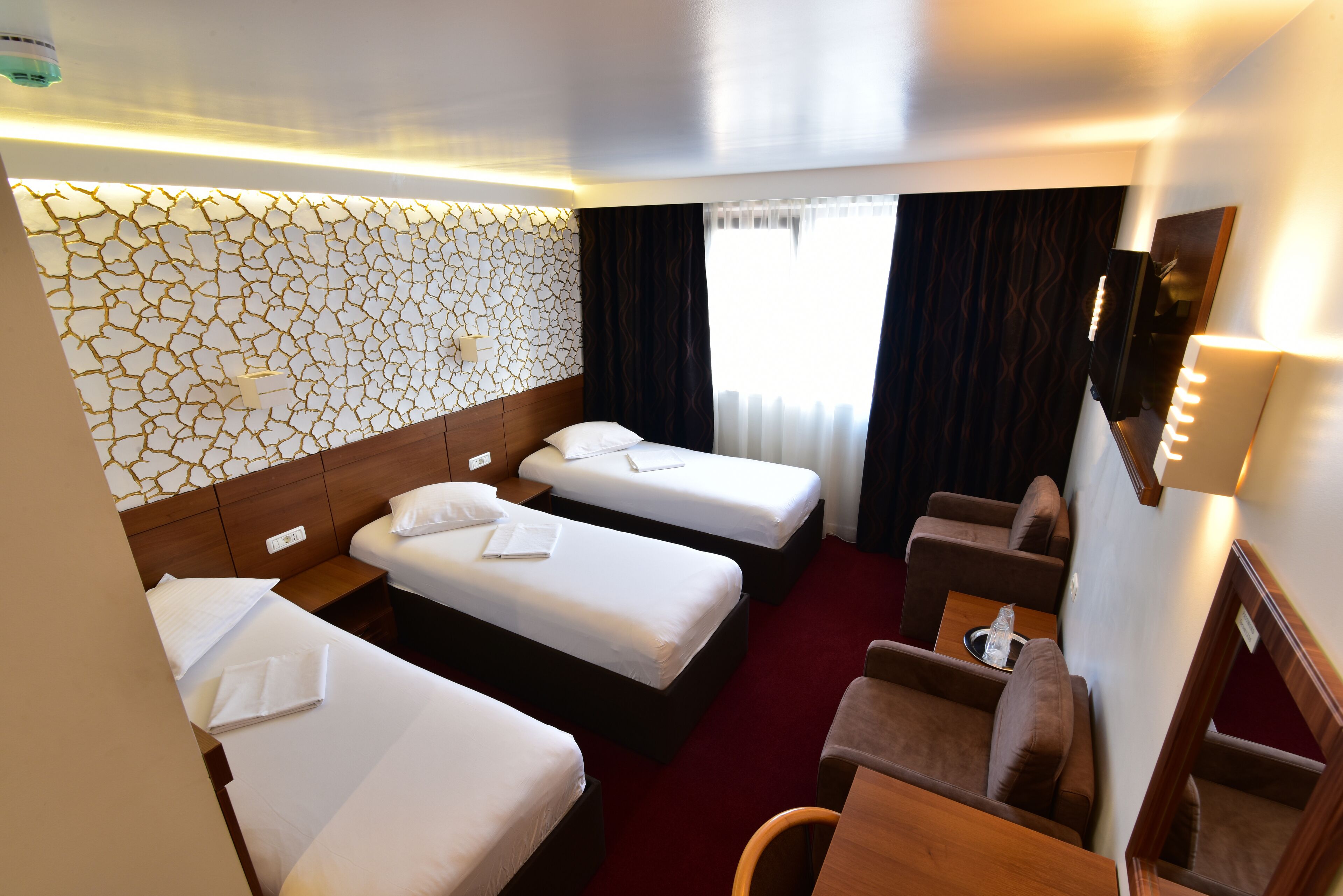 A hotel room with two single beds, a sofa, a small table, and a mirror.