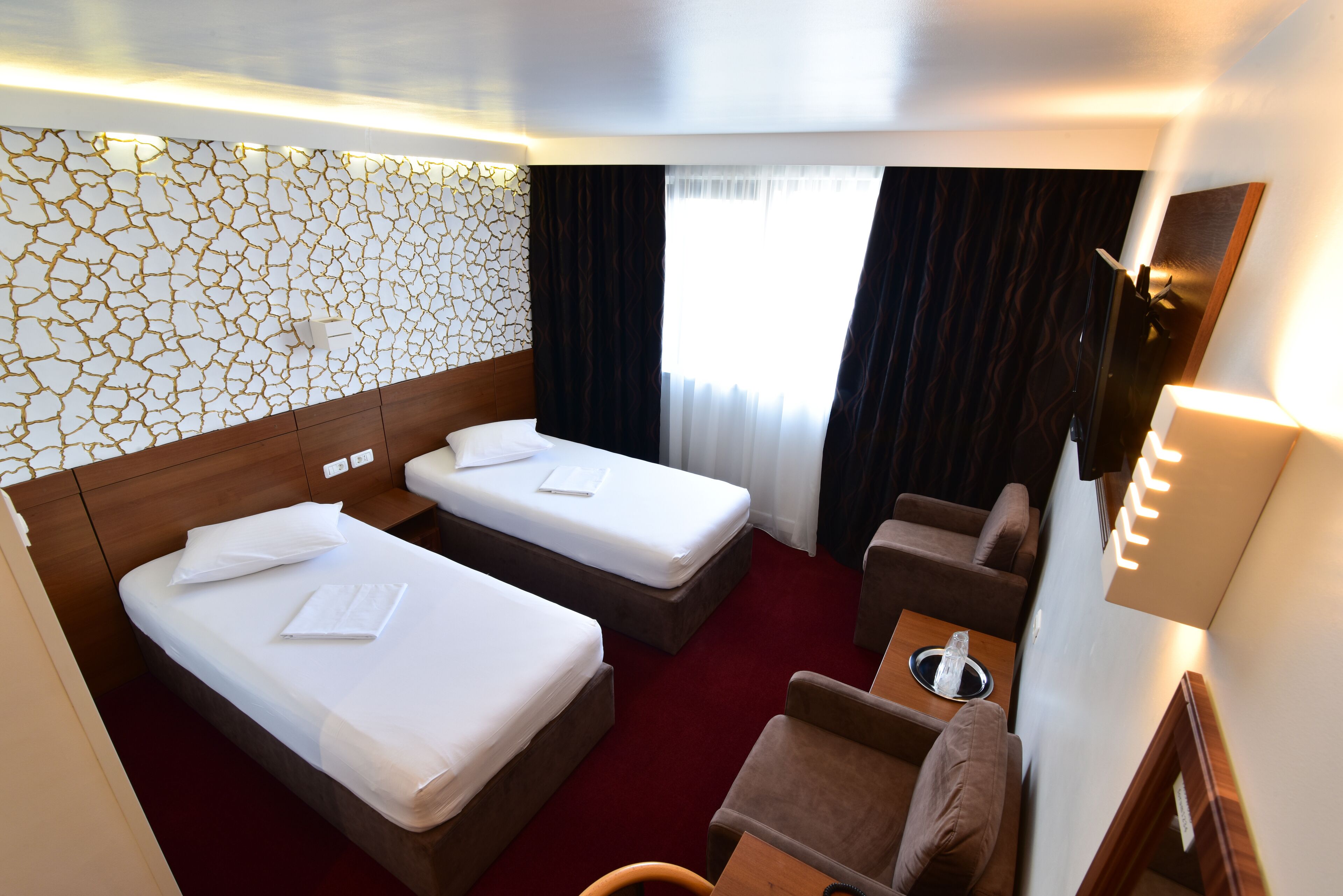 A hotel room with two beds, a sofa, a small table, and a mirror.
