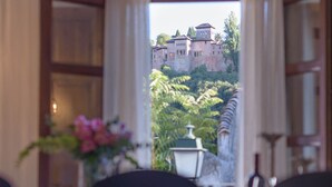Une table à manger avec des chaises et un vase de fleurs, dans laquelle se reflètent un château et la verdure en arrière-plan.