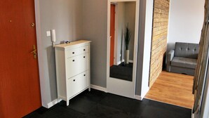 A hallway with a white dresser, a grey sofa, and a wooden accent wall. - HelApartamenty - Apartament Bałtyk (Hel)