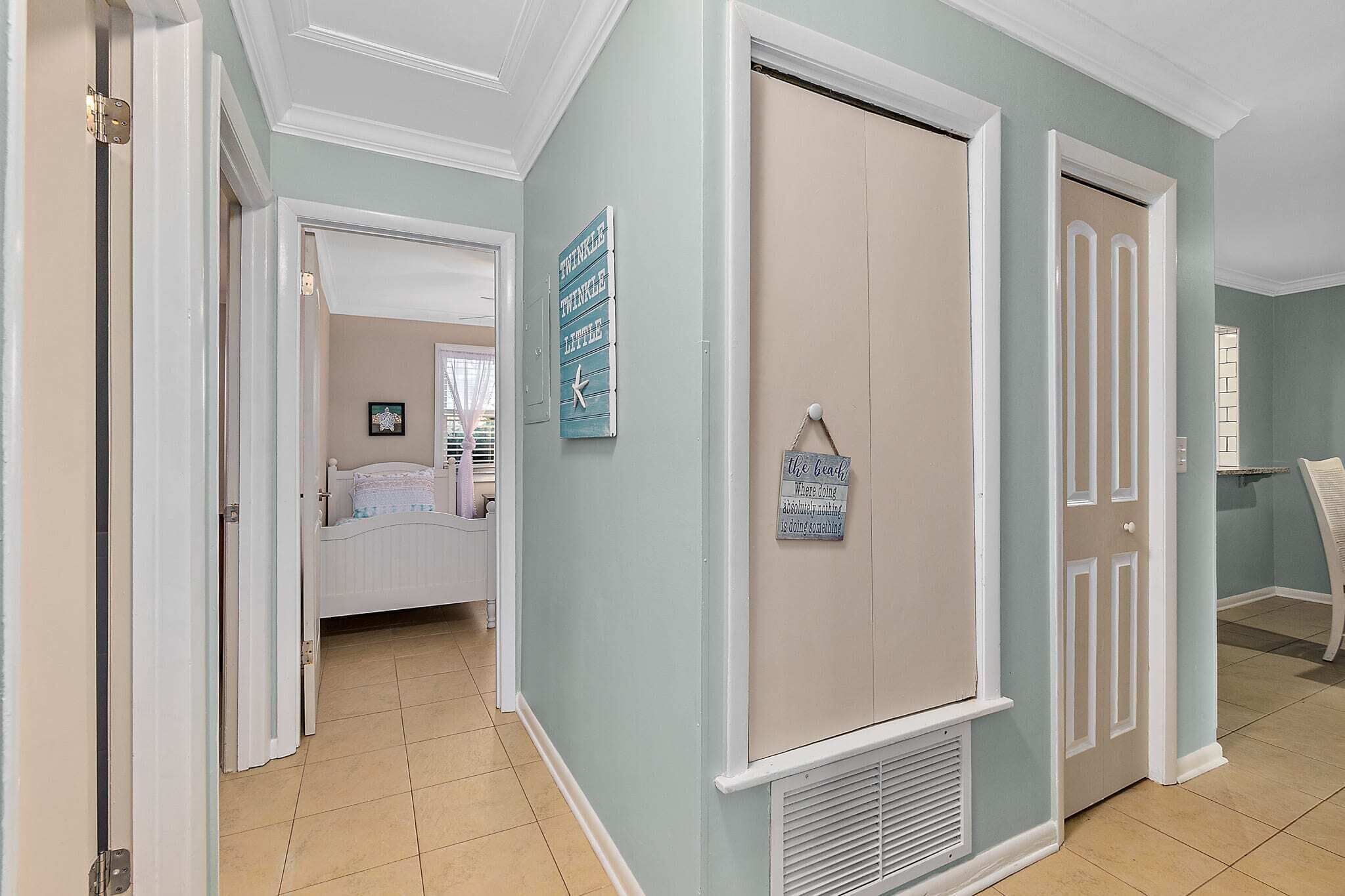 A hallway with a bed, a closet, and a sign on the wall.
