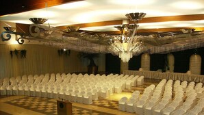 A large hall with rows of white chairs, a checkered floor, and a chandelier.