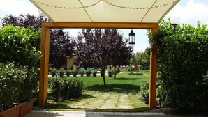 A covered outdoor area with a wooden pergola, a pathway, and surrounding greenery.