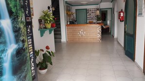 A hotel lobby with a reception desk, a staircase, and a fire extinguisher on the wall. - Hostal Manolo (Garrucha)