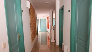 A hallway with teal doors, a patterned wall, and a tiled floor. - Hostal Manolo (Garrucha)