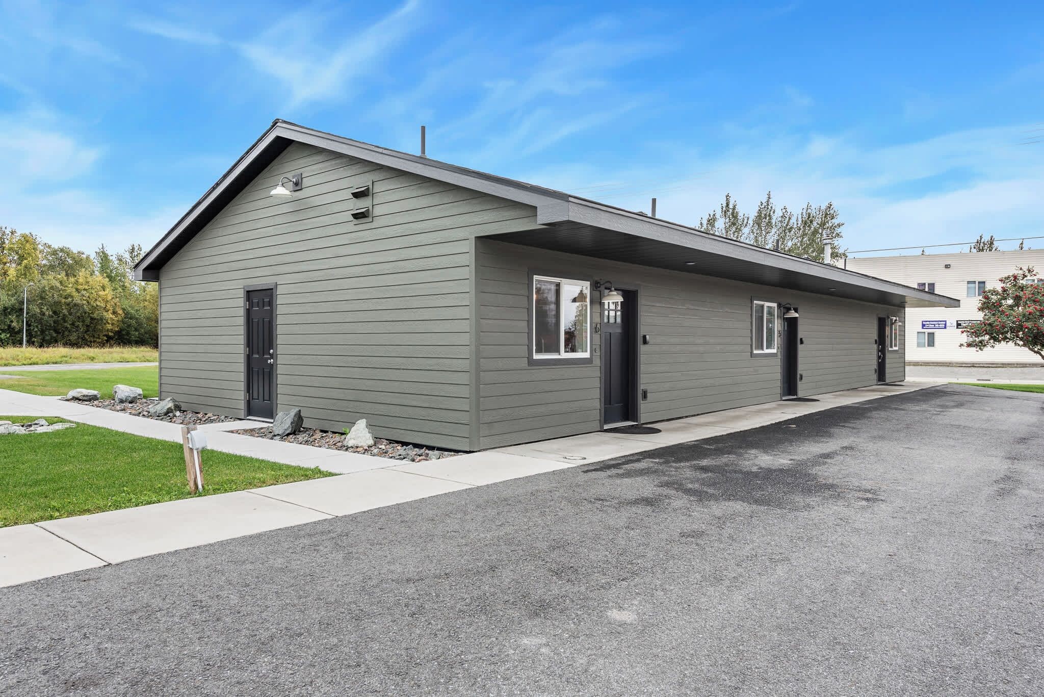 A two-story building with a flat roof, a single entry door, and a small porch area.