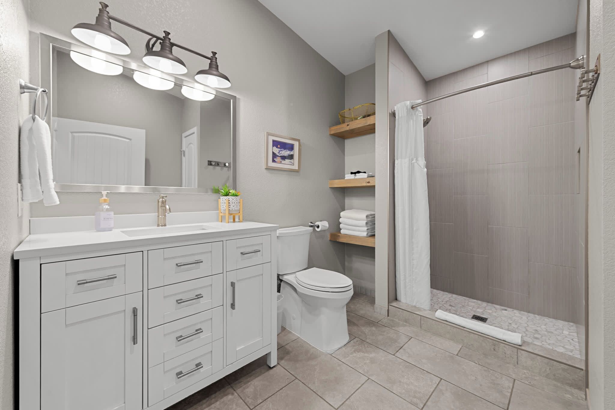 A modern bathroom with a vanity, toilet, and shower area.