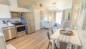 Una cucina moderna con elettrodomestici in acciaio inossidabile, un'area pranzo con tovaglia a quadri e vista sul soggiorno.