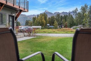 A view from a balcony overlooking a grassy area with a mountain range in the background. - Mt. Views • Downtown Walkable • Kitchen • Laundry! (Palmer)