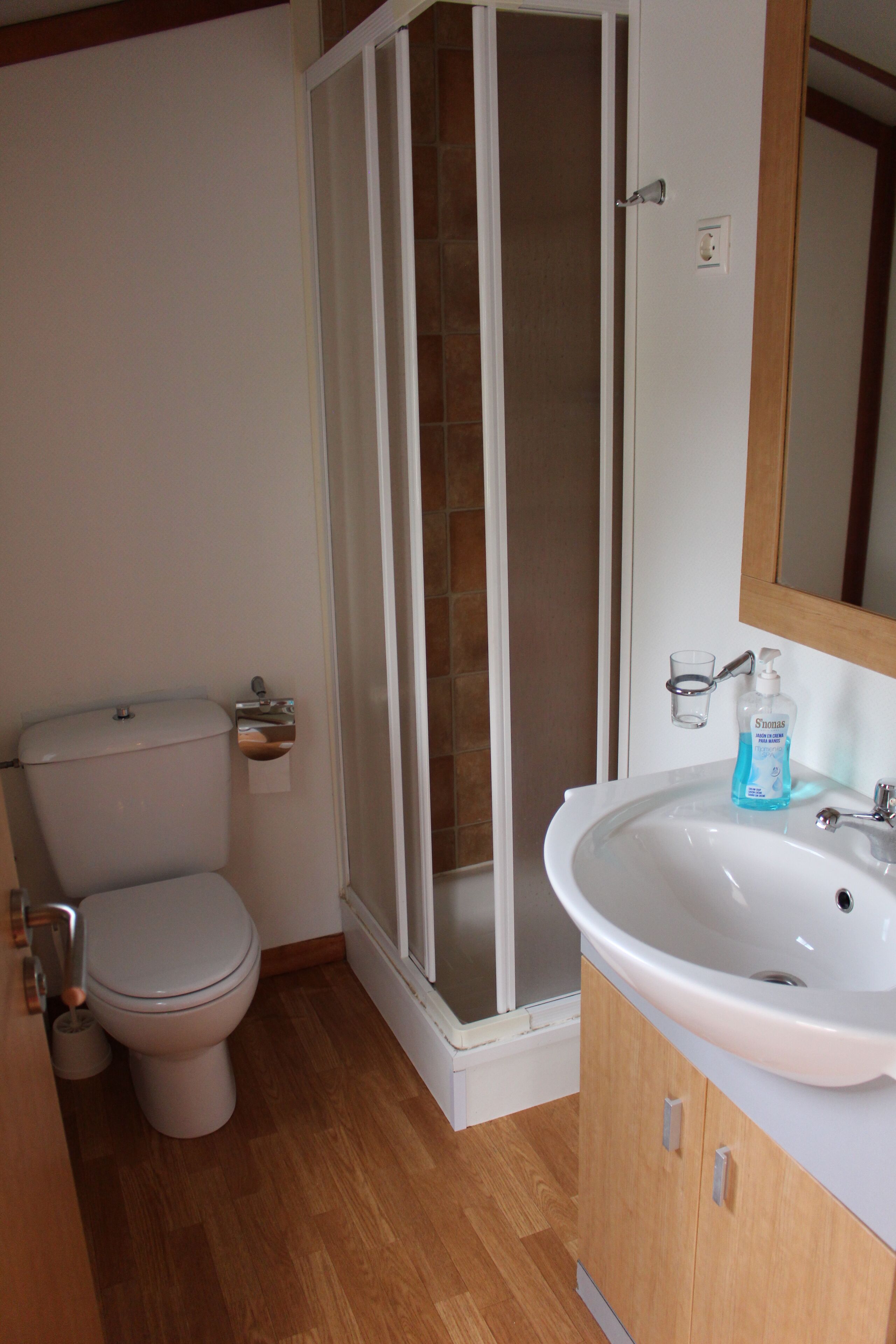 A bathroom with a toilet, a shower, and a sink.