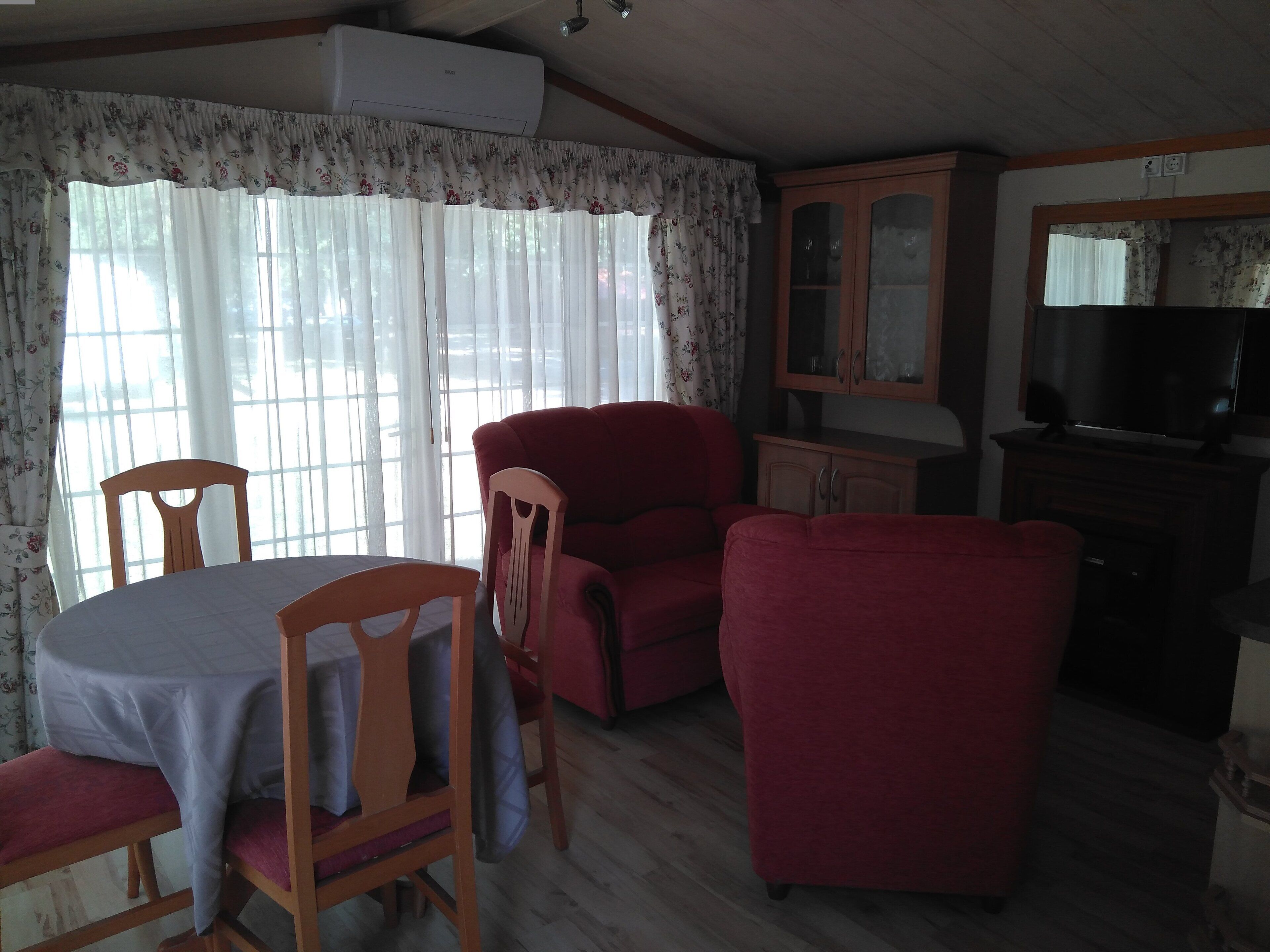 A living room with a dining table, two chairs, a red armchair, and a cabinet.