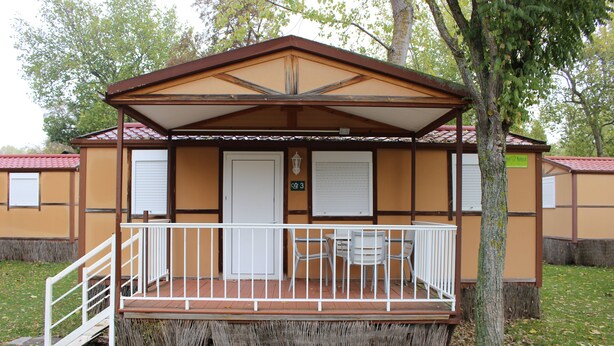 En liten, envåningsbyggnad med en veranda, ett vitt räcke och en skylt som visar siffran 3.