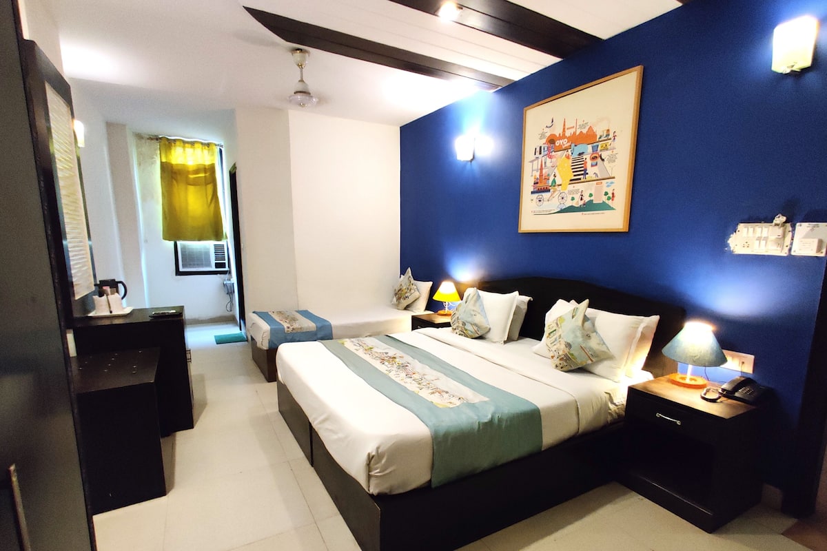A hotel room with a large bed, bedside tables with lamps, a ceiling fan, and a wall with a framed picture.