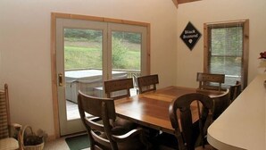 A dining area with a wooden table and chairs, a glass door leading outside, and a sign on the wall that reads "Black Diamond." - NF31-Slopeside Home! Hot Tub! A/C, Fire Pit! (Davis)