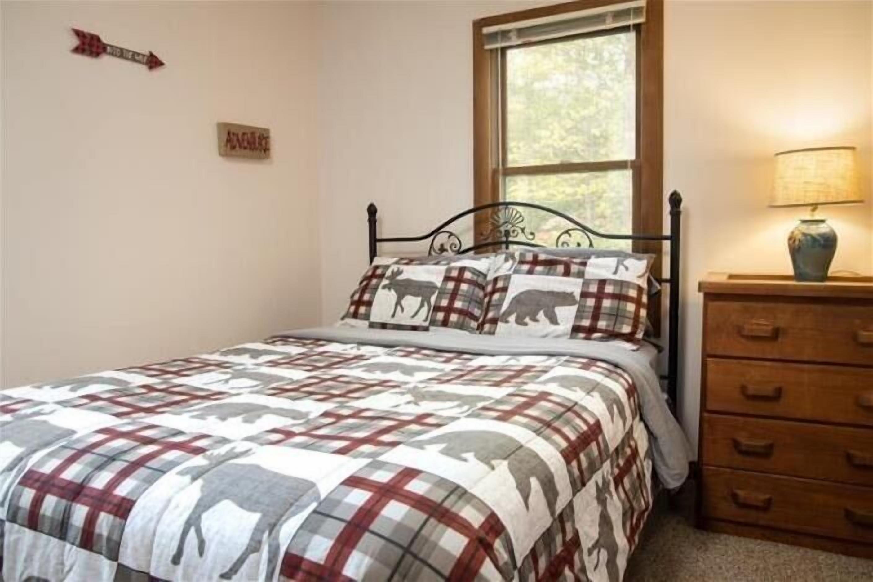 Un dormitorio con cama, ventana, cómoda y un cartel en la pared.