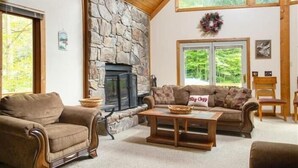 A cozy living room with a stone fireplace, a sofa, and a coffee table. - NF31-Slopeside Home! Hot Tub! A/C, Fire Pit! (Davis)