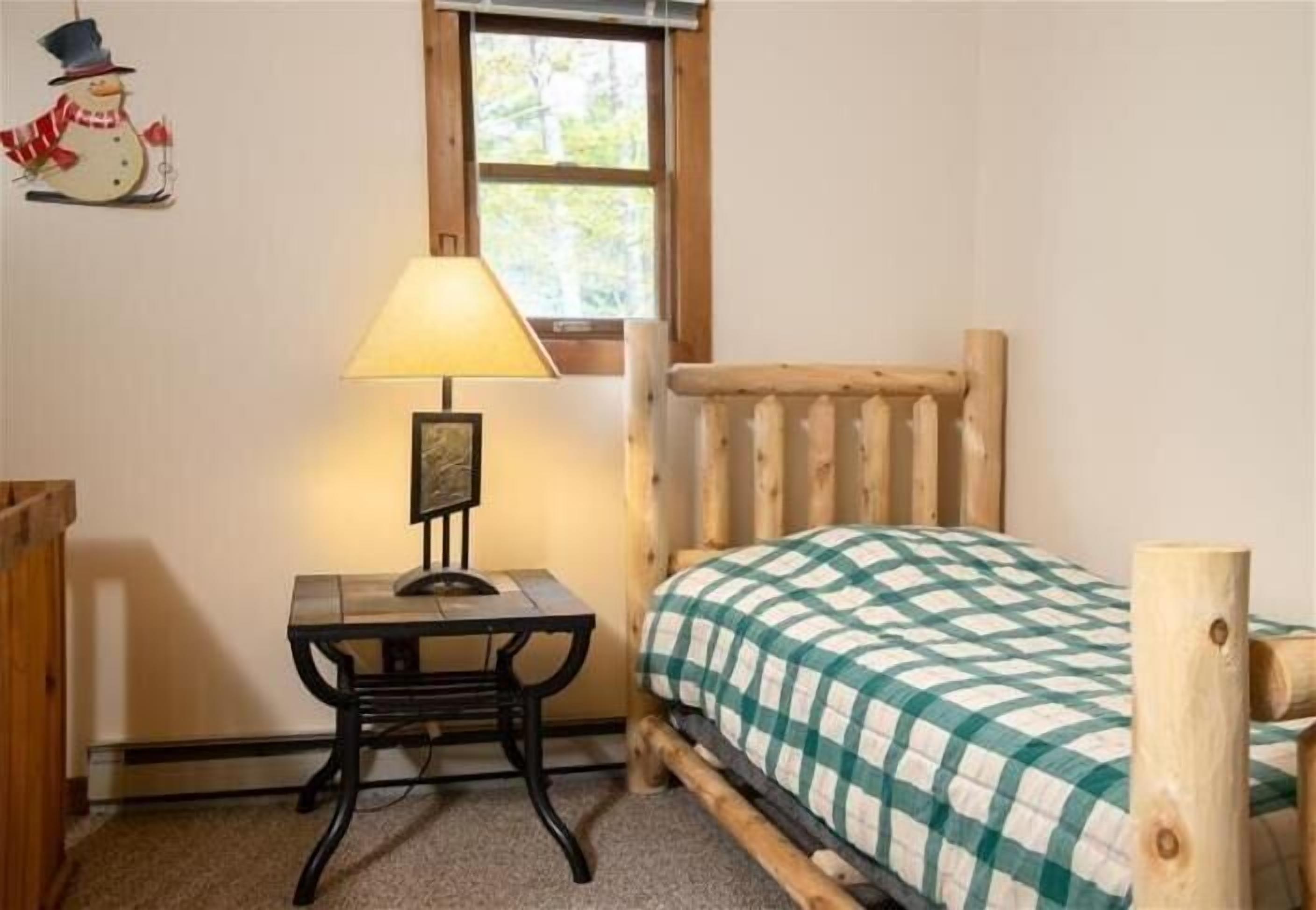 Una habitación acogedora con una cama de madera, una mesita con una lámpara y un marco de fotos.