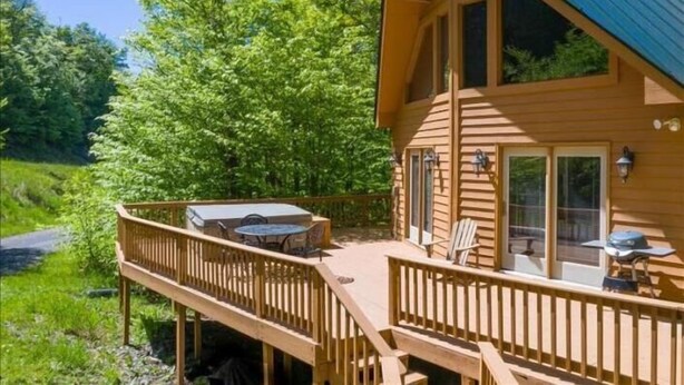 A wooden cabin with a deck, large windows, and a covered outdoor area. - NF31-Slopeside Home! Hot Tub! A/C, Fire Pit! (Davis)