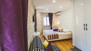 Une chambre à coucher avec un lit, une armoire, une petite table et une fenêtre avec des rideaux.