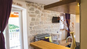 Une cuisine avec un plan de travail en bois, un vase contenant des fleurs séchées et un mur en pierre.