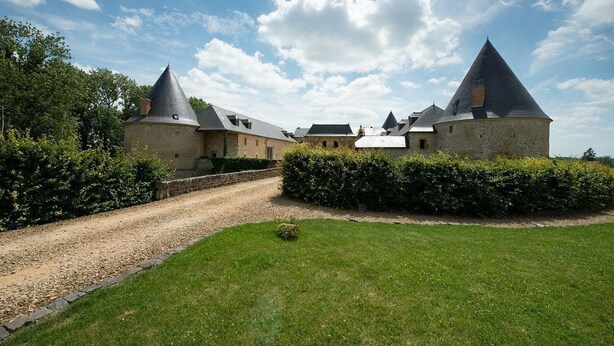 A historic building with multiple towers and a gravel driveway. - Large gîte with indoor swimming pool (Charbogne)