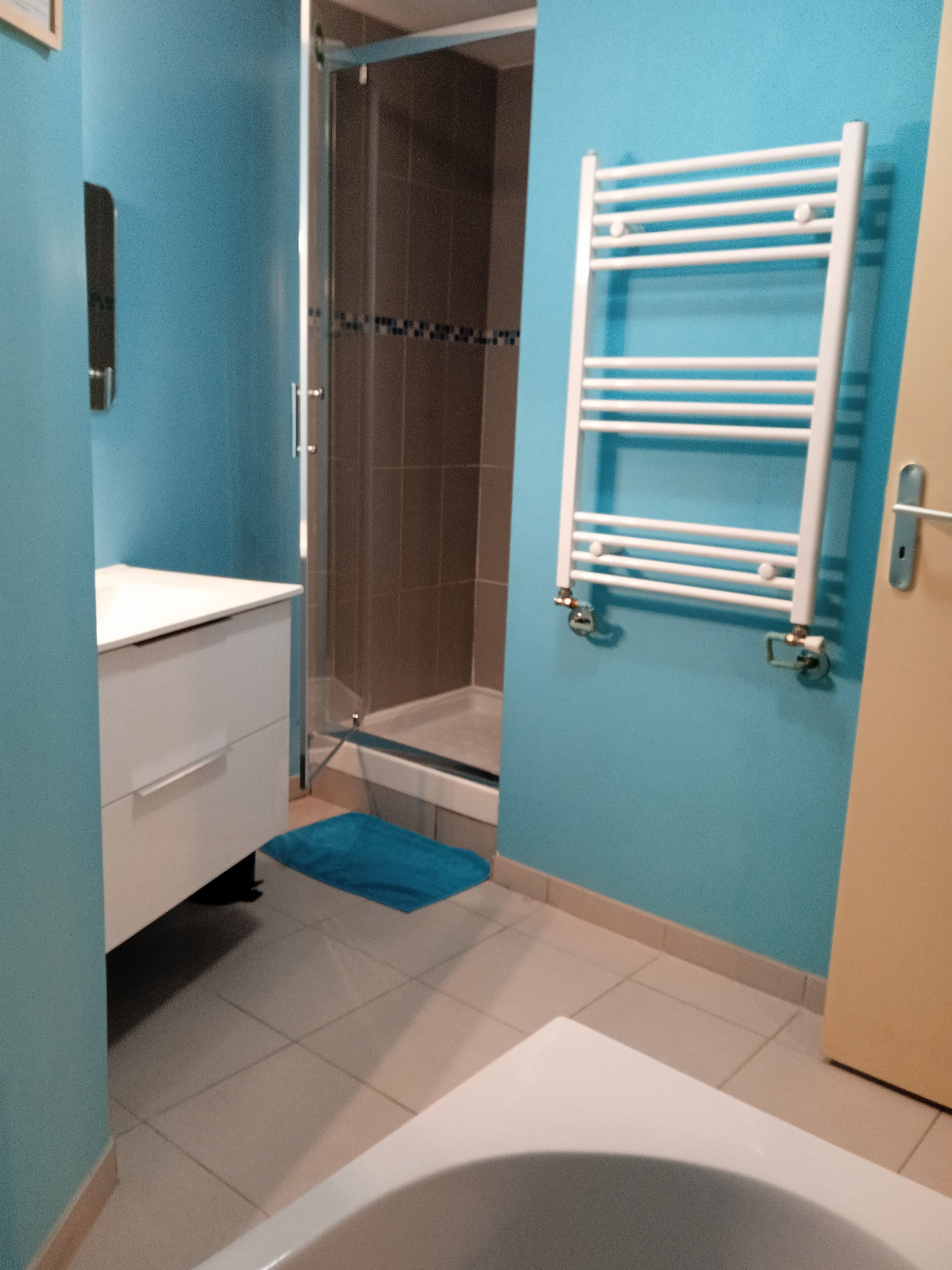 A bathroom with a bathtub, a shower, a towel rack, and a sink.