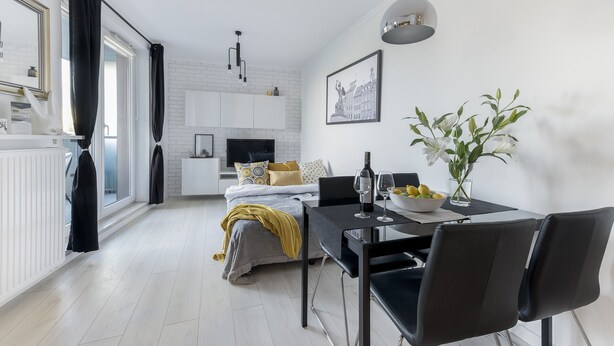 A modern, well-lit room with a dining table, chairs, a sofa, and a bed. - P&O Apartments Metro Wilanowska 4 (Warsaw)