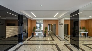 A modern hotel lobby with a marble floor, wooden accents, and a reception desk. - P&O Apartments Metro Wilanowska 4 (Warsaw)