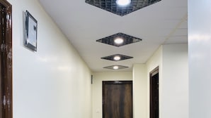Un pasillo con suelo de mármol, una puerta de madera al final y una planta en maceta a la derecha.