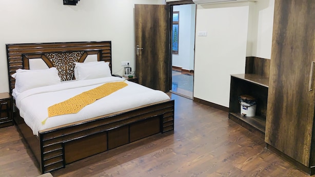 Un dormitorio ordenado con una cama de madera, una mesita de noche con lámpara y un armario.