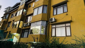 Un edificio amarillo de varios pisos con múltiples ventanas y unidades de aire acondicionado.