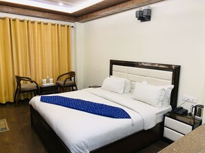 Une chambre d’hôtel comprenant un lit, deux chaises, une table de chevet et une petite table avec une bouilloire et un téléphone.