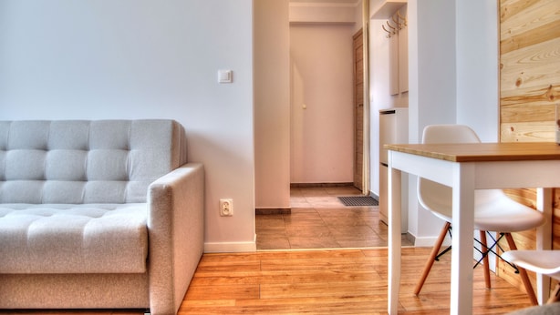En moderne stue med en grå sofa, et træspisebord og en hvid stol.