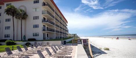 A hotel with multiple balconies, a beachside location, and sun loungers.