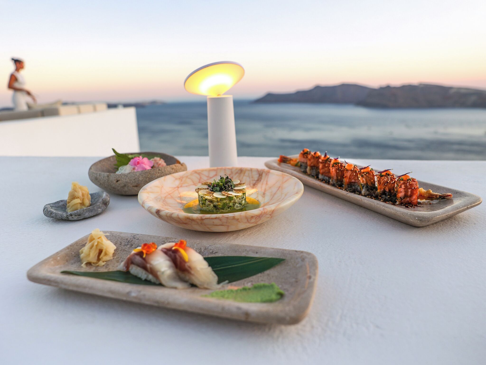 A table with various dishes, a candle, and a view of the sea.