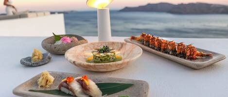 A table with various dishes, a candle, and a view of the sea.