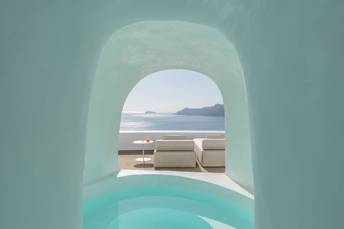A modern, minimalist room with a view of the sea and distant mountains.