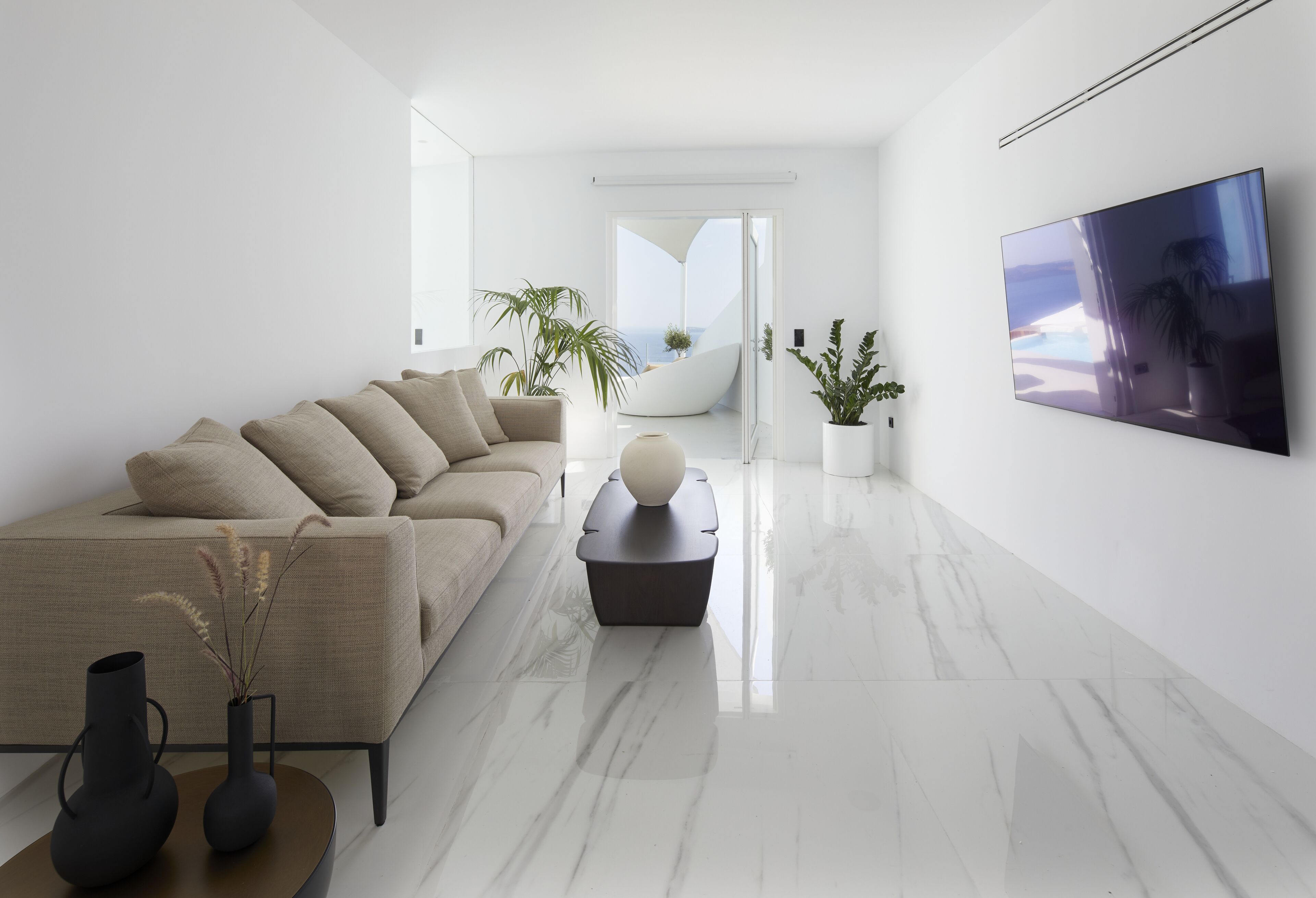 A modern living room with a sofa, a coffee table, and a TV on the wall.