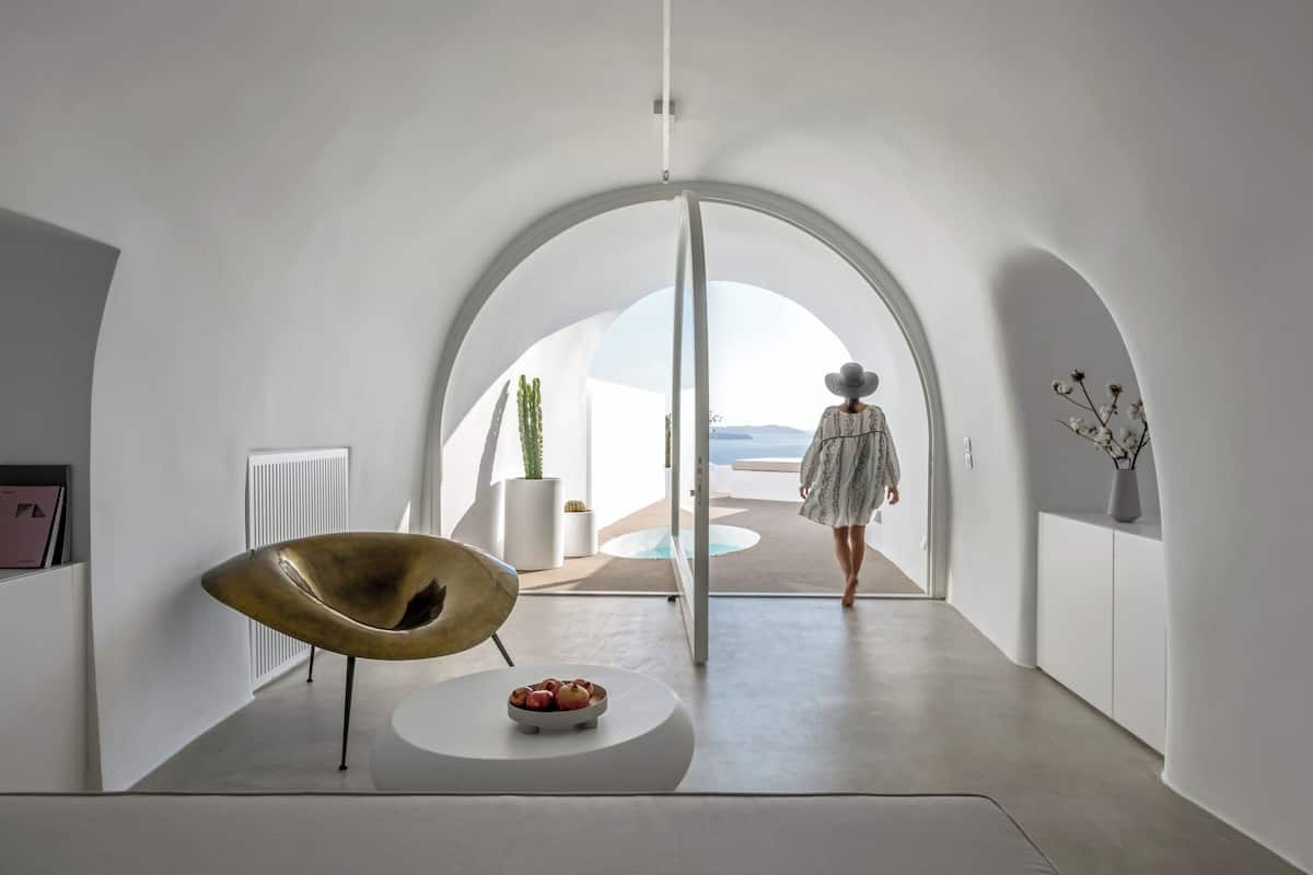 A modern interior with a curved ceiling, a central seating area with a bowl of fruit, and a view of the outdoors.