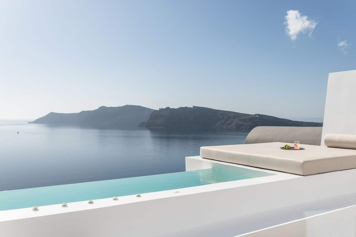 A modern infinity pool with a clear view of the sea and distant mountains.