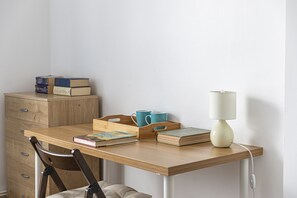 Een houten bureau met een lamp, boeken en een dienblad voor een mok.