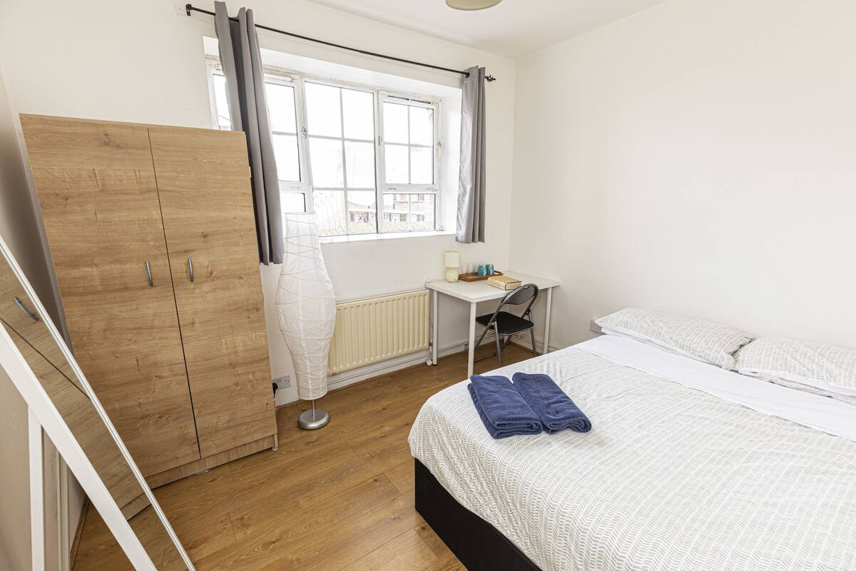 A bedroom with a bed, a desk, a chair, and a wardrobe.